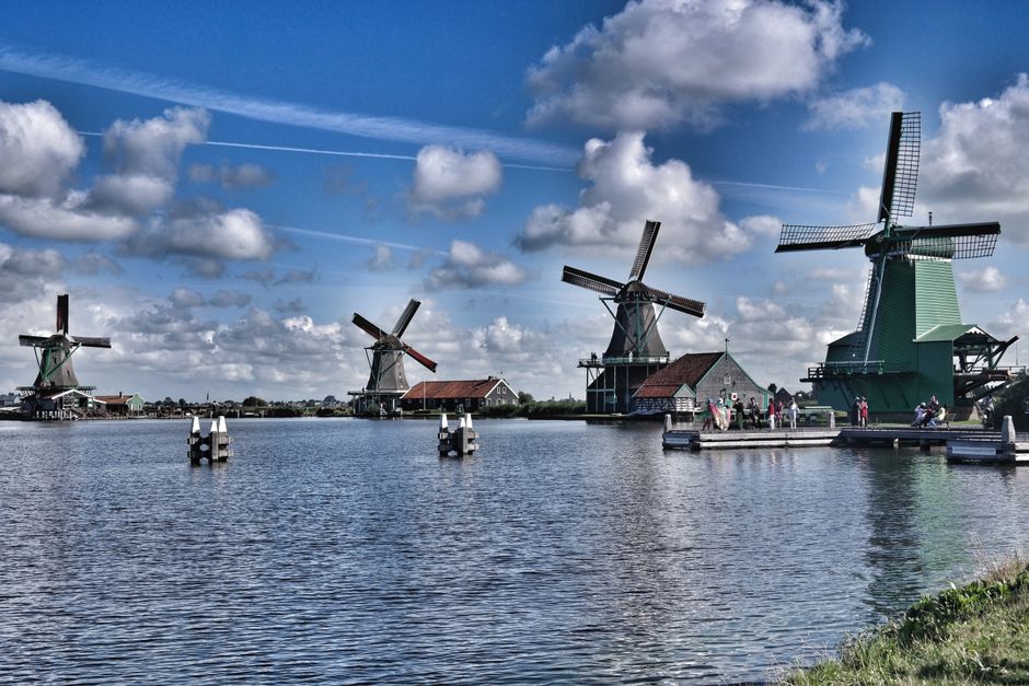 Picturesque windmills and reflections in water at Zaanse Schans, Netherlands, showcasing iconic Dutch landscape.