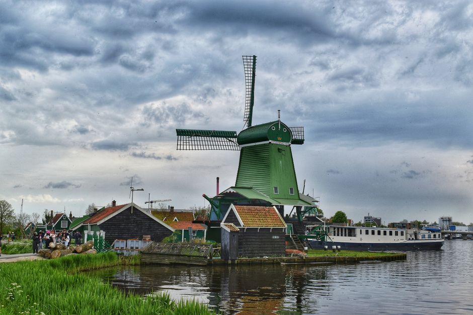Scenic view of a traditional green windmill at Zaanse Schans under an overcast sky.
